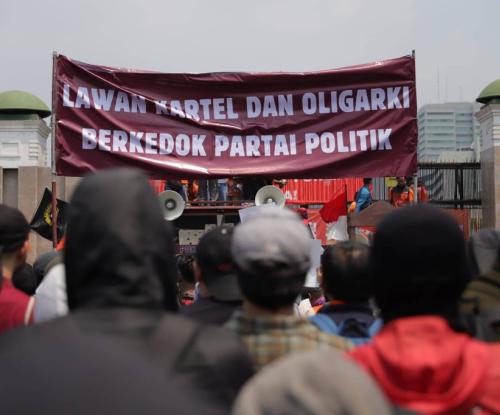 peserta aksi 22 Agustus 2024 membentangkan banner di depan gedung DPR dengan tulisan "Lawan Kartel dan Oligarki Berkedok Partai Politik"