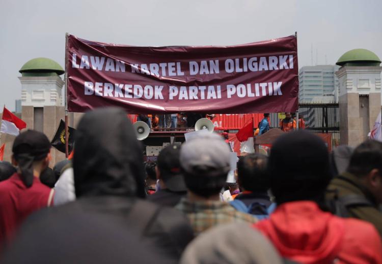 peserta aksi 22 Agustus 2024 membentangkan banner di depan gedung DPR dengan tulisan "Lawan Kartel dan Oligarki Berkedok Partai Politik"